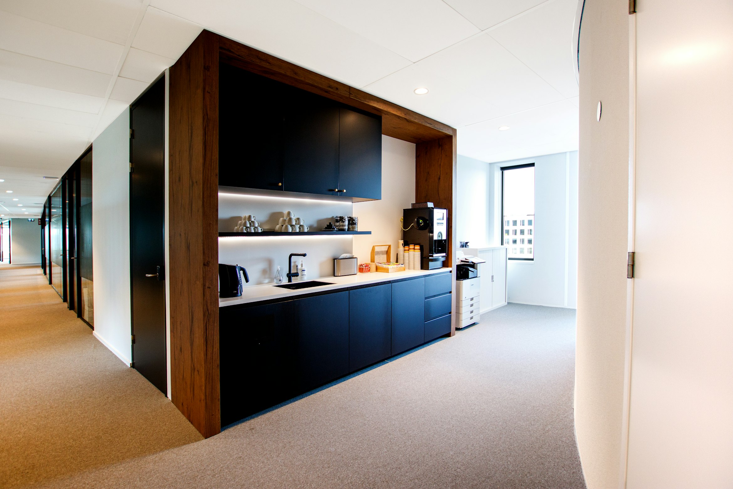 Office kitchenette and coffee bar with navy cabinetry