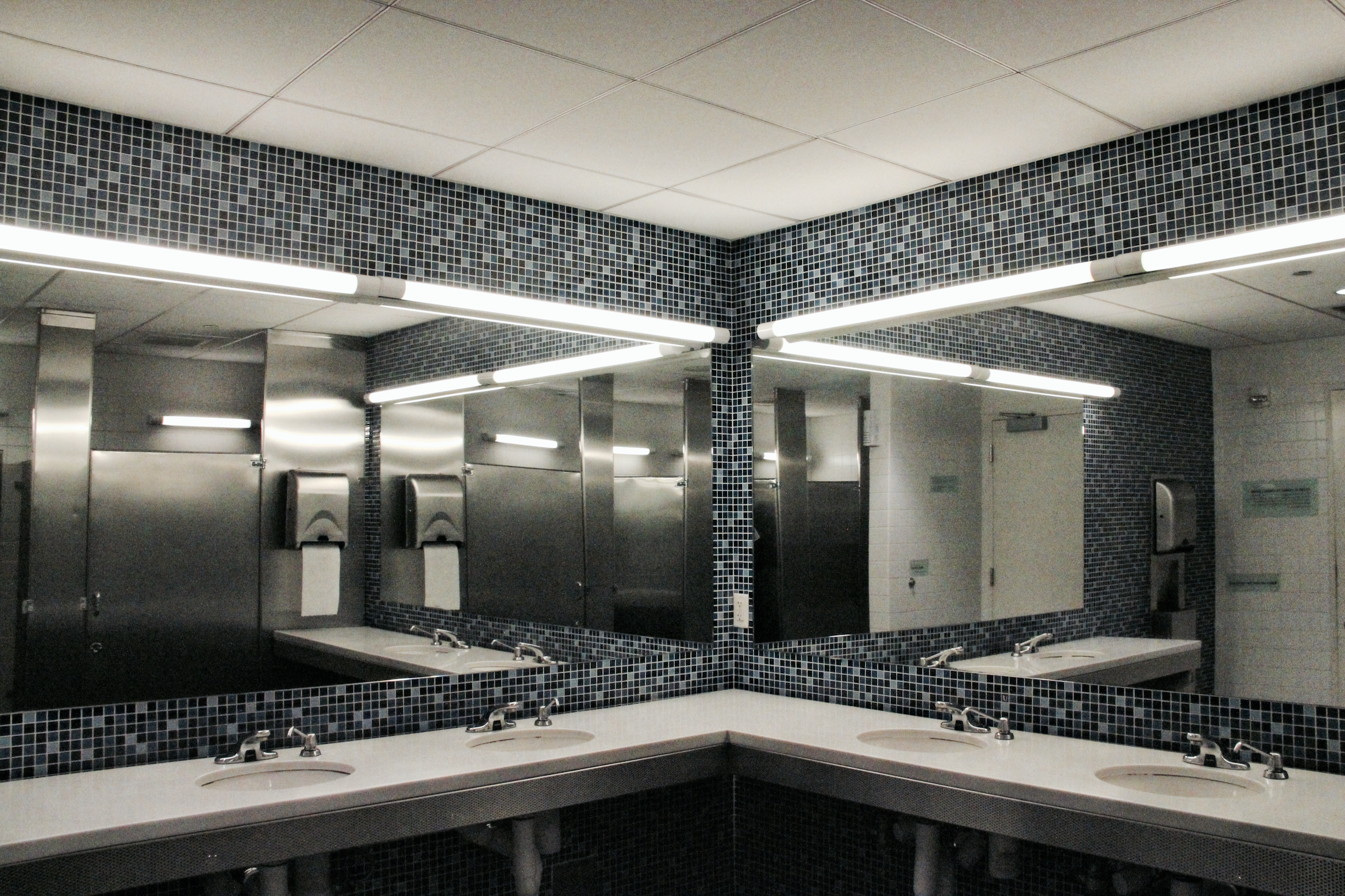 Washroom with mosaic tile and multiple mirrors and sinks